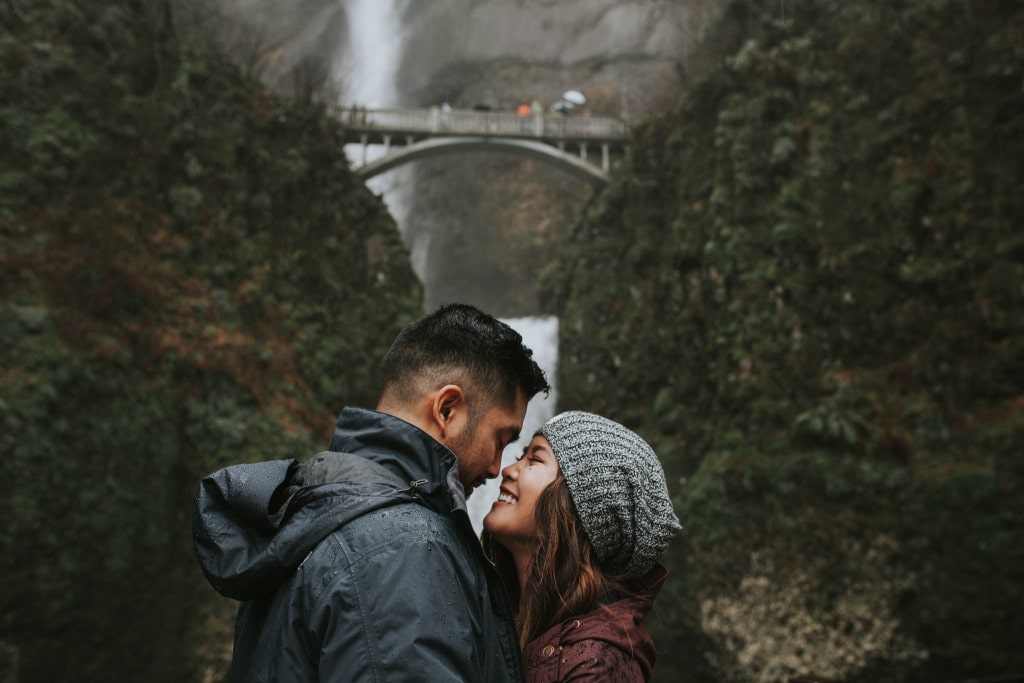 cute couple smiling in front of Multnomah Falls by Marcela Pulido Portland Wedding Photographer