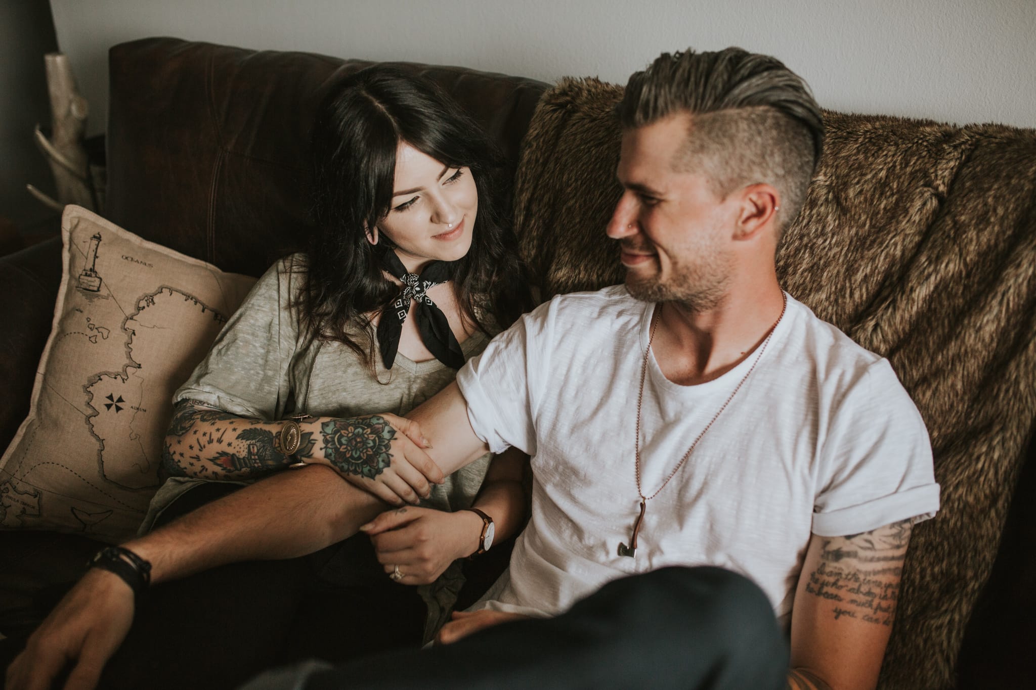 image of an adorable and edgy couple with tattoos cuddling on the couch captured by portland wedding photography pricing by marcela pulido