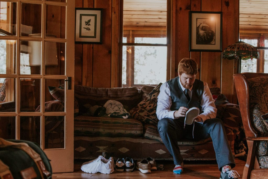 groom putting on shoes getting ready in cabin Estes Park Rocky Mountain Wedding Photographer