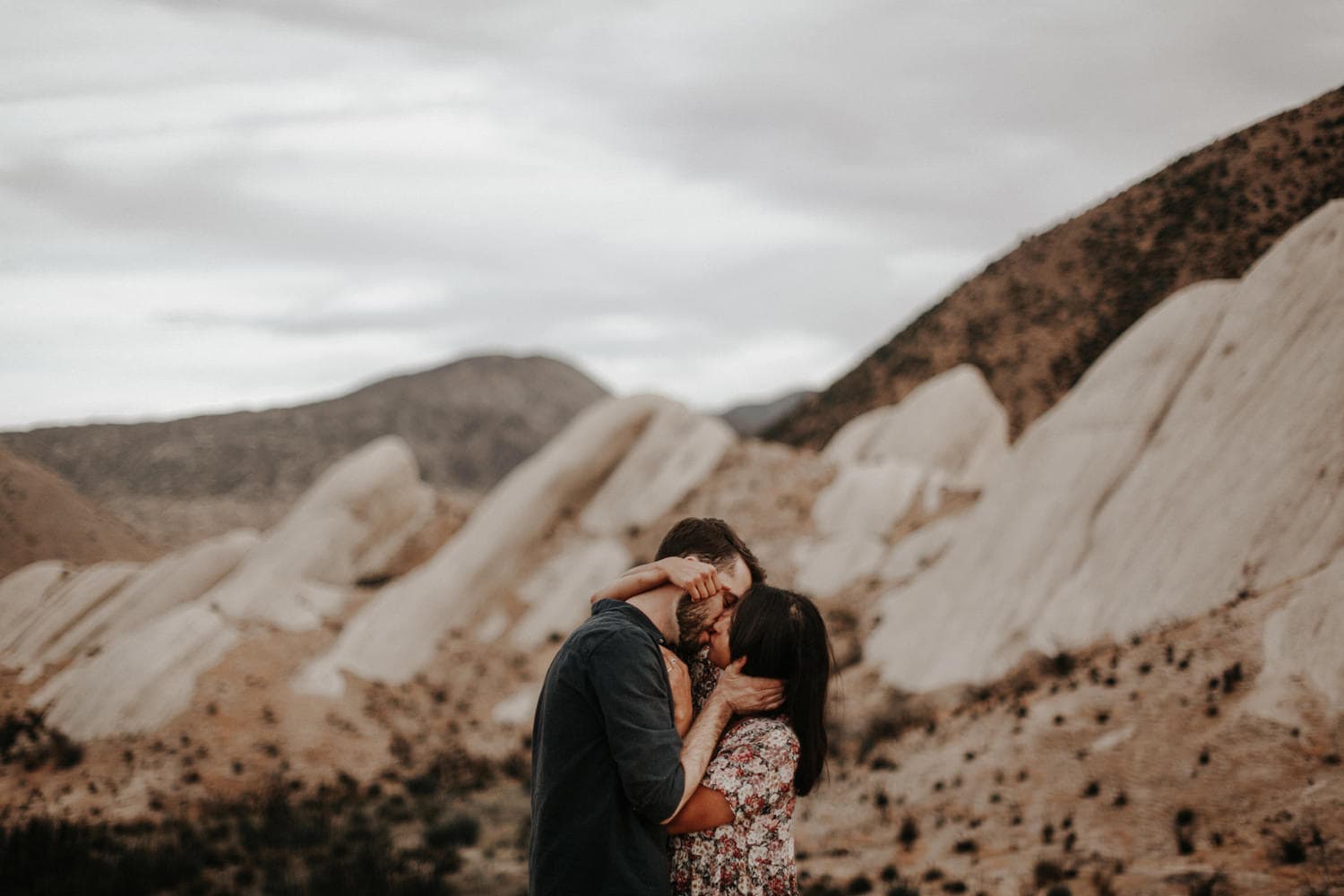 beautiful intimate shot of couple with limbs entwined and kissing at sunset in the san bernardino mountains at mormon rocks