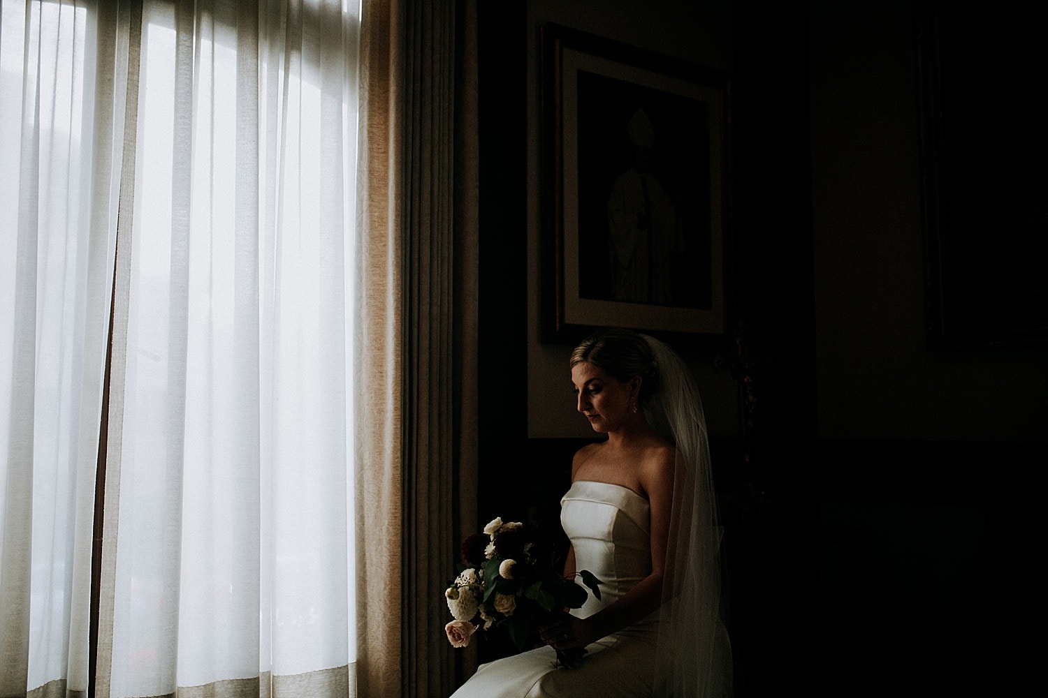 dark low light portrait of the bride before her ceremony sitting in front of a window at St James Cathedral 415 Westlake Wedding by Marcela Pulido Seattle Wedding Photographer