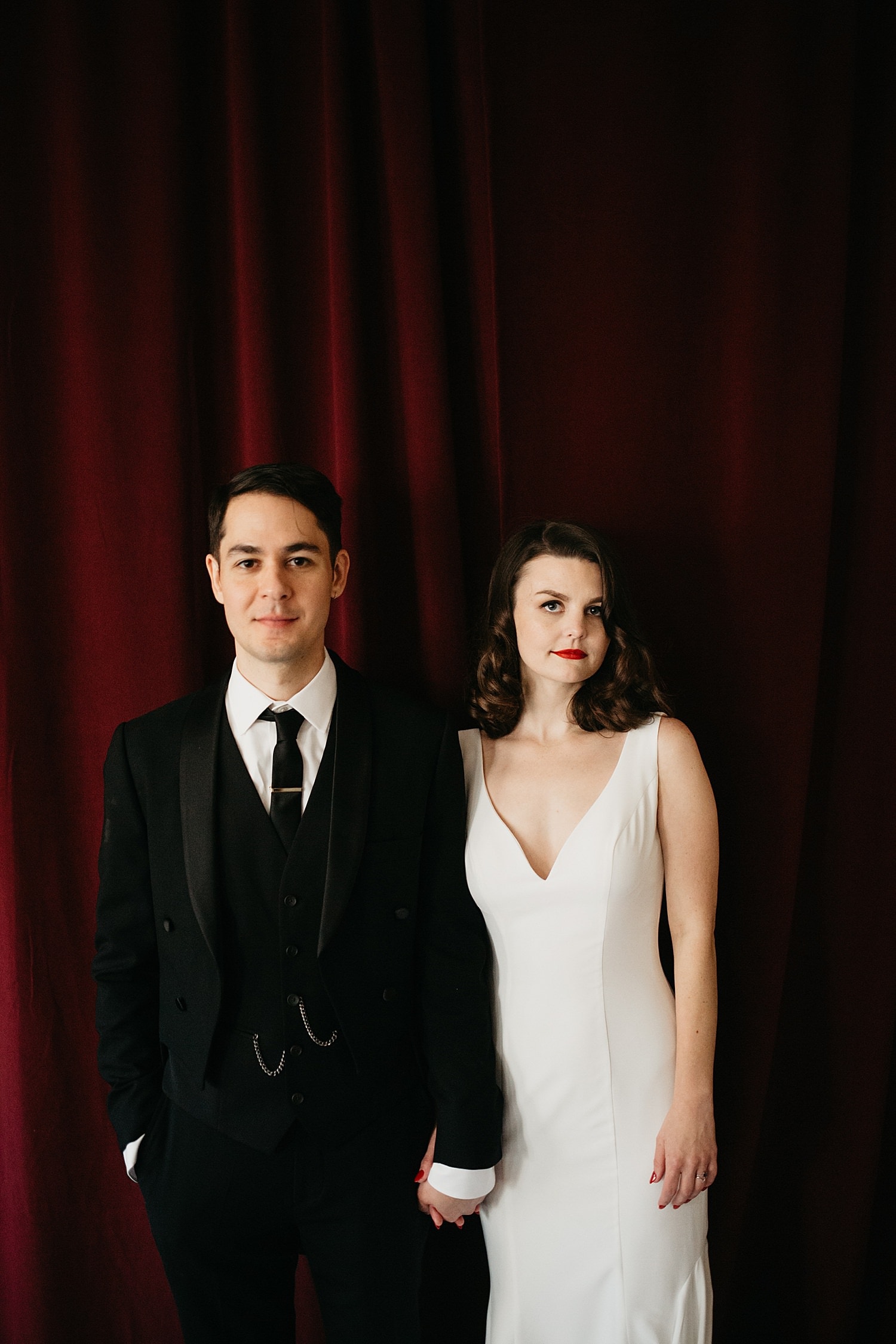 portrait of a bride and groom in front of a red velvet curtain Melody Ballroom wedding by Marcela Pulido Photography