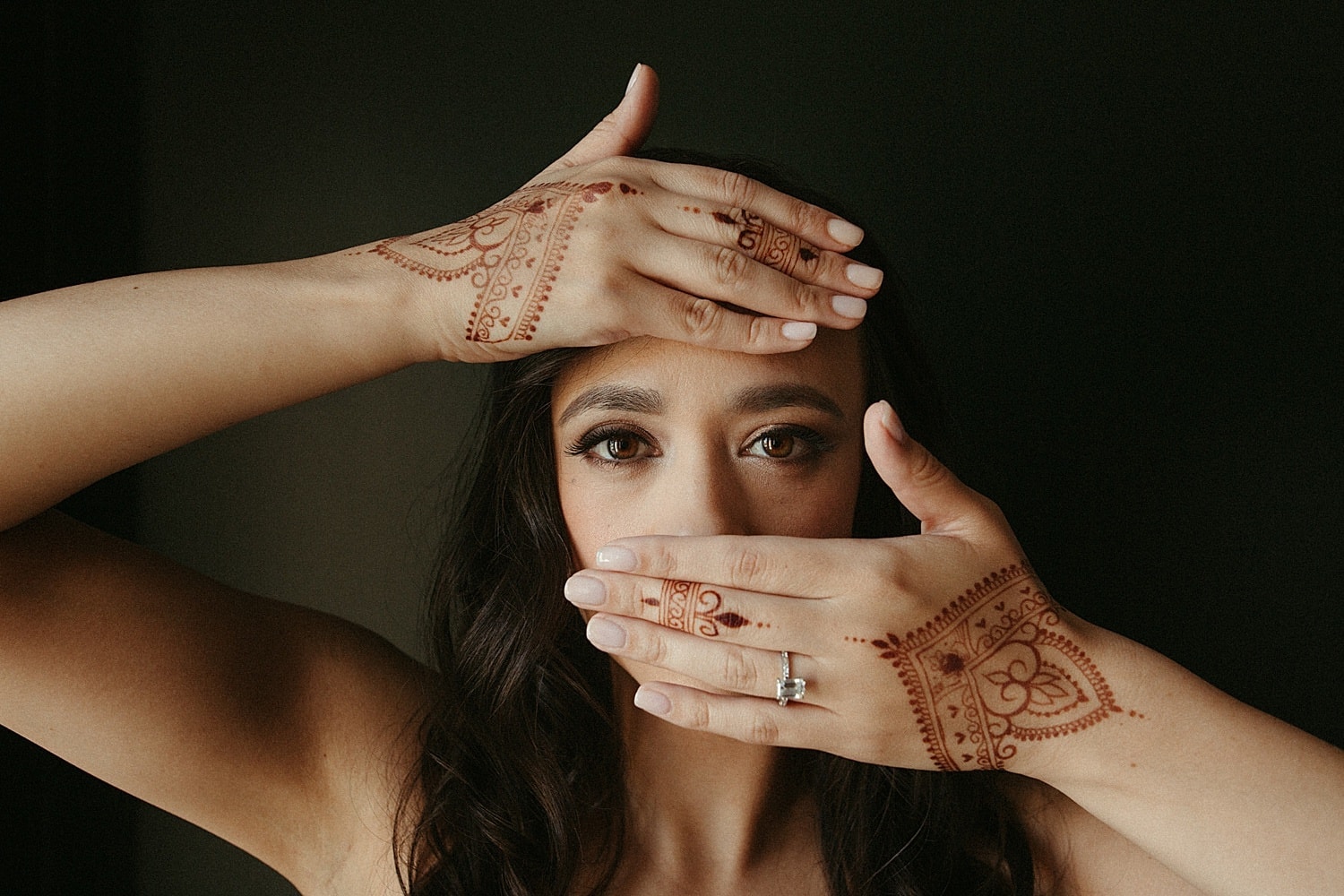 bride with henna on her hands portrait against a dark wall by marcela pulido photography portland wedding photographer