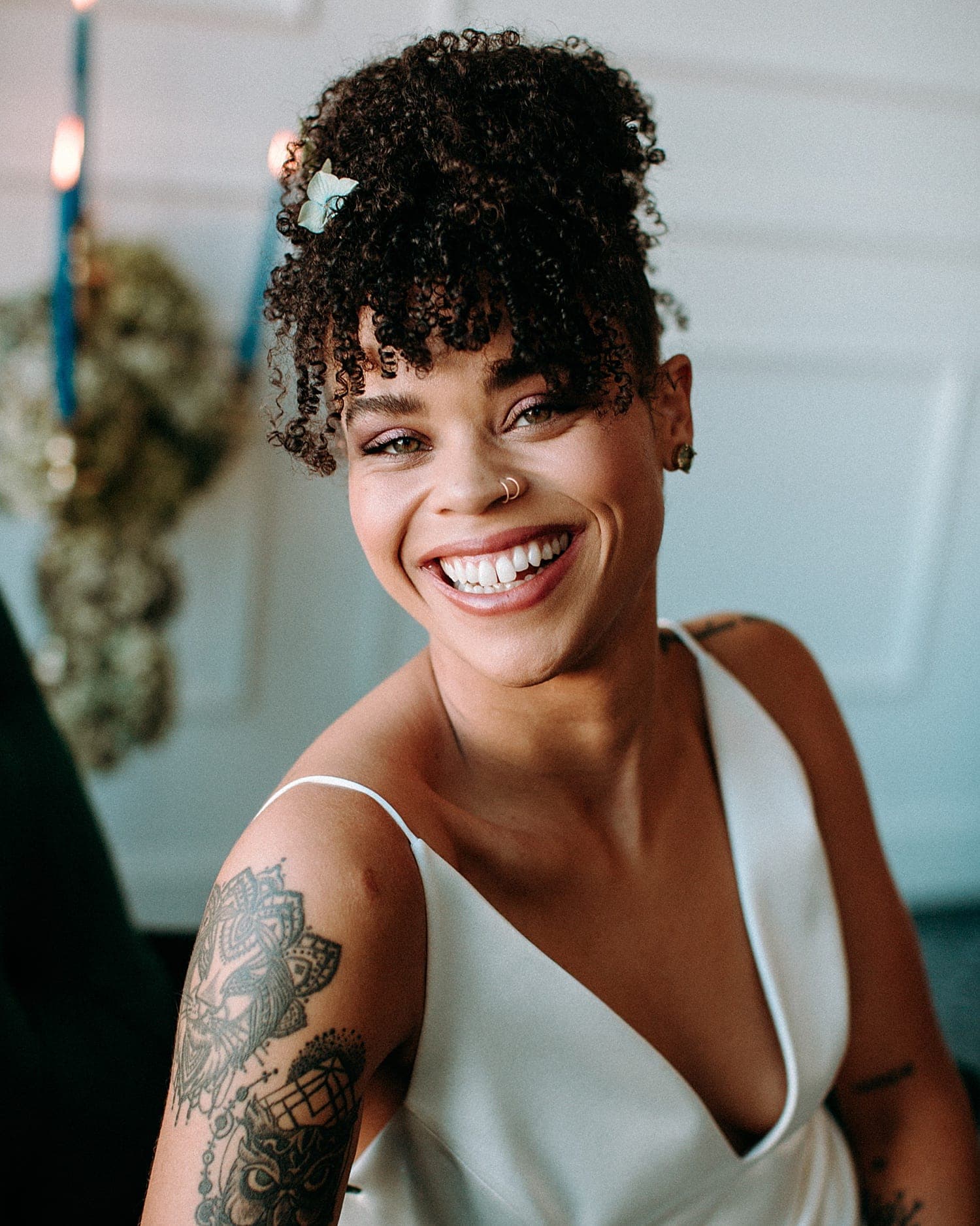 black bride grinning portrait with curly hair and hazel colored eyes sitting on a teal velvet couch