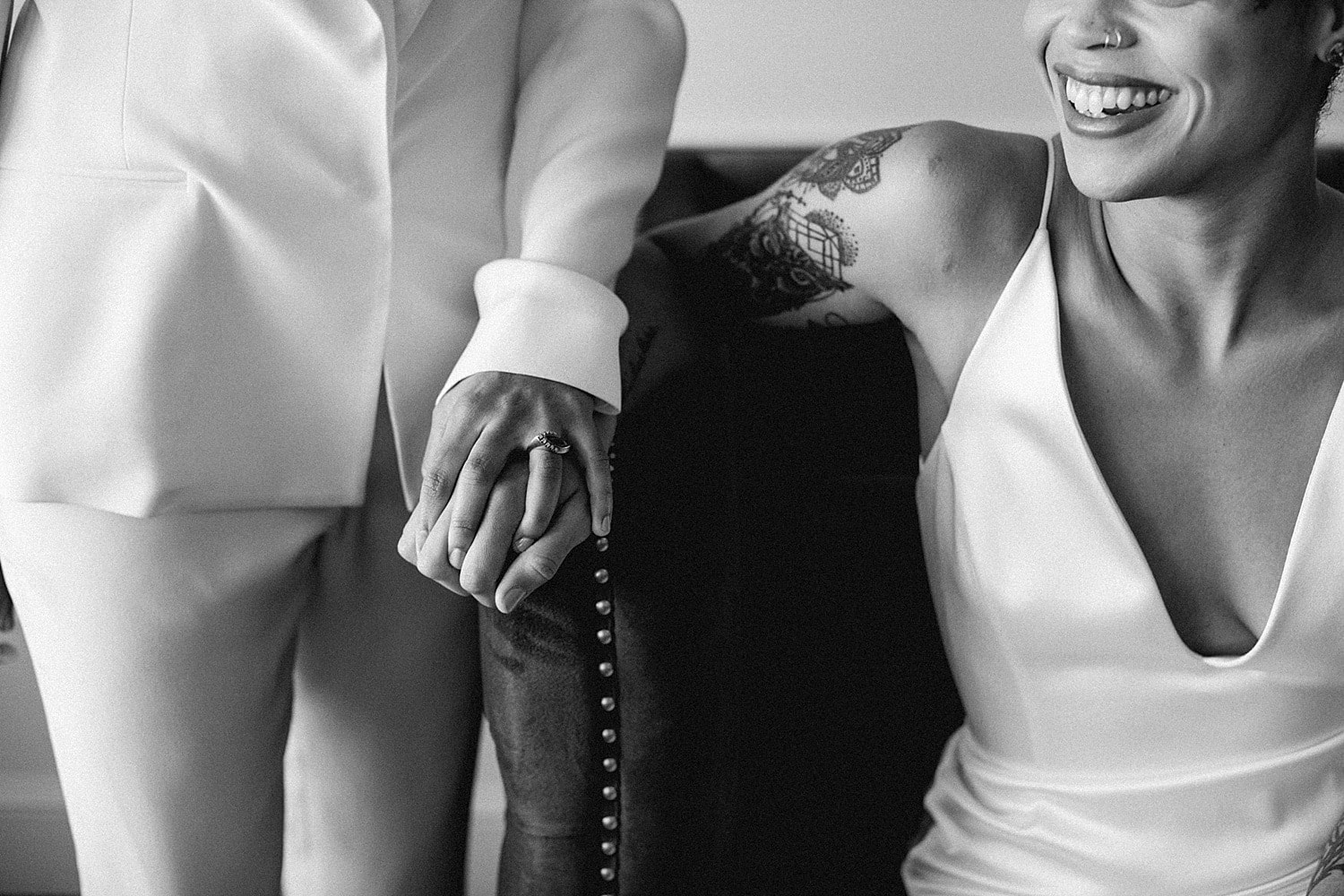 black and white portrait if same sex lesbian lgbtq+ brides holding hands and laughing