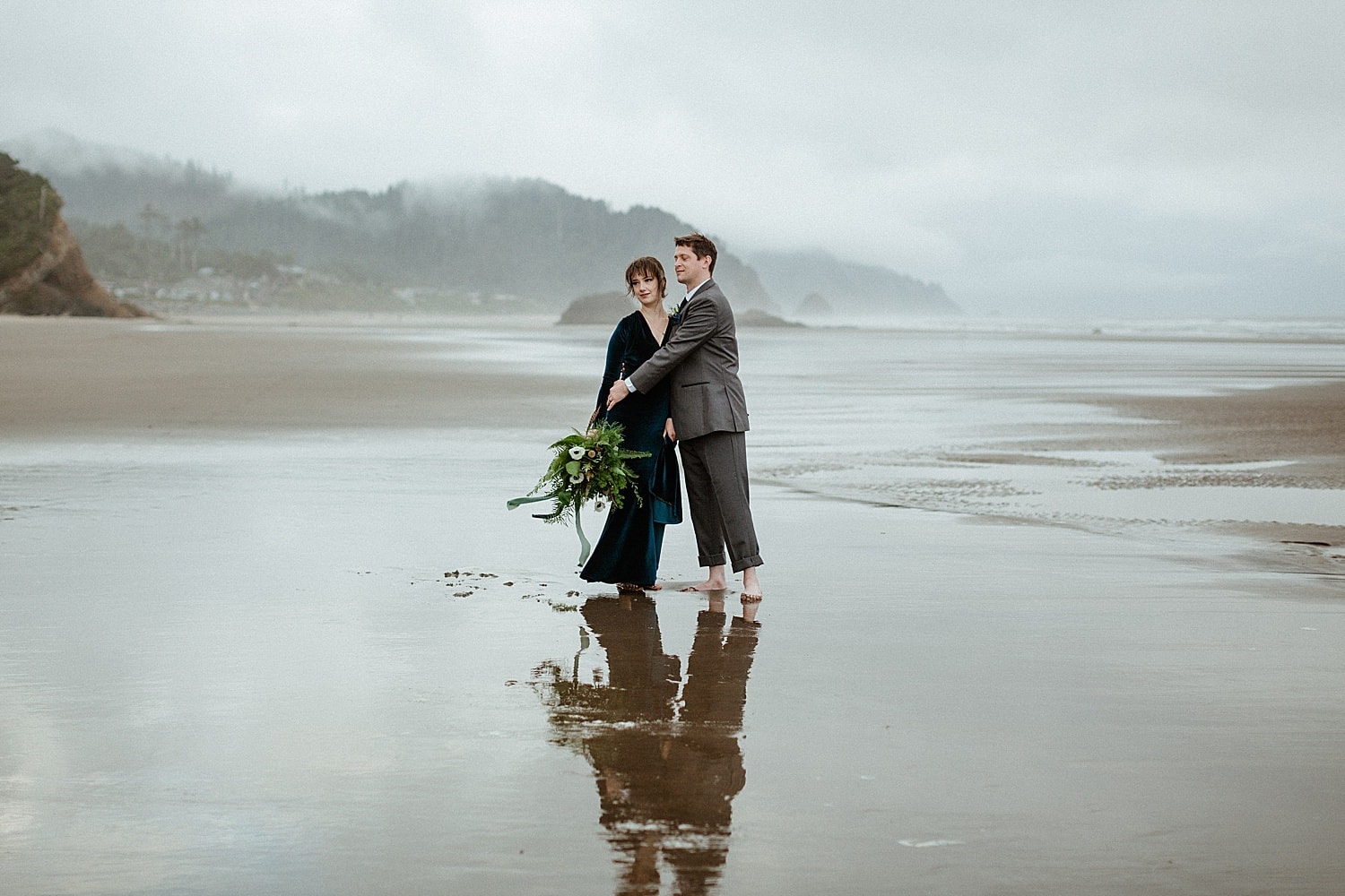 beautiful newlywed couple embracing on a foggy oregon coast blue velvet wedding dress captured by marcela pulido photography portland oregon wedding elopement photographer