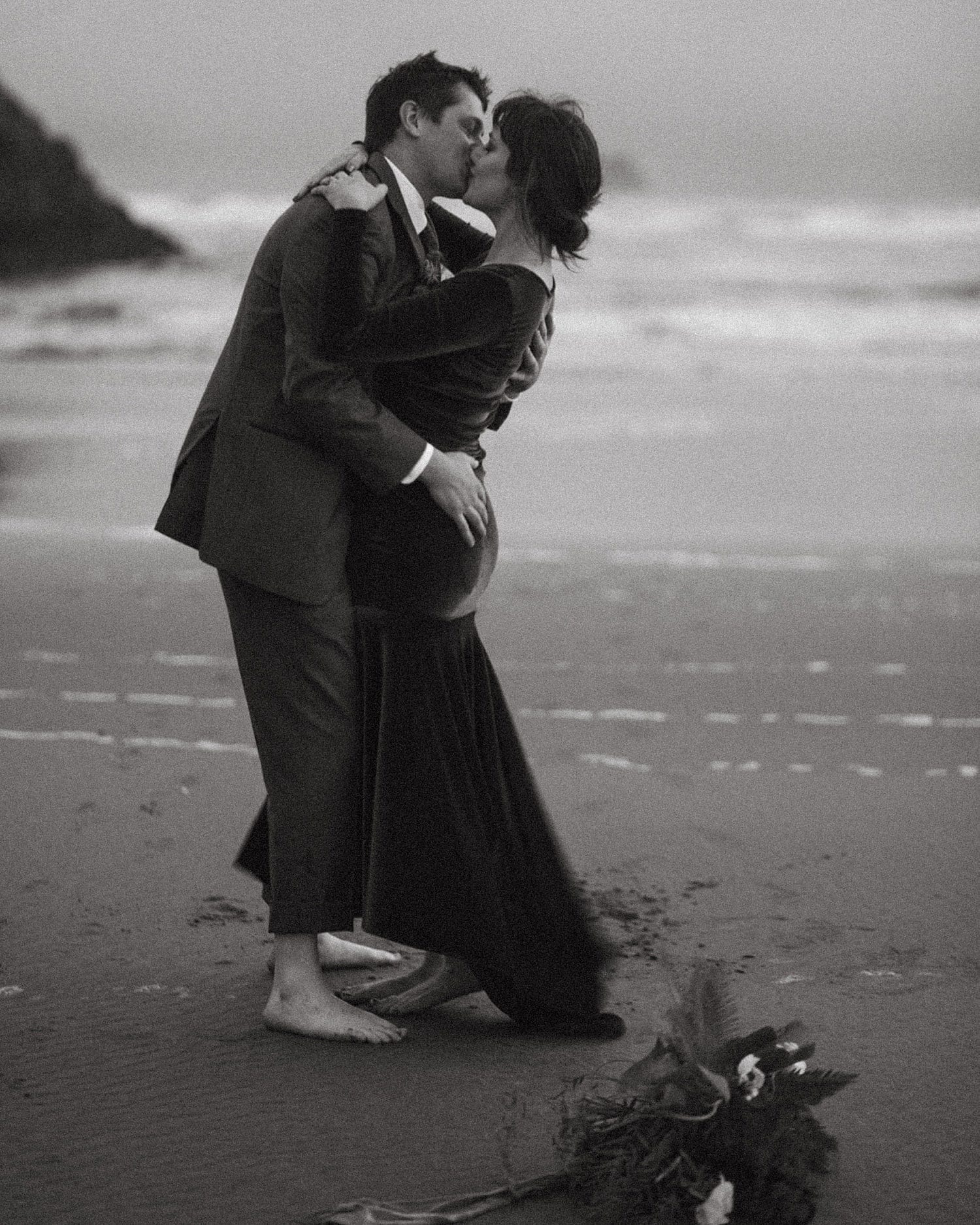moody black and white portrait of newlywed couple embracing on the oregon coast by marcela pulido photography