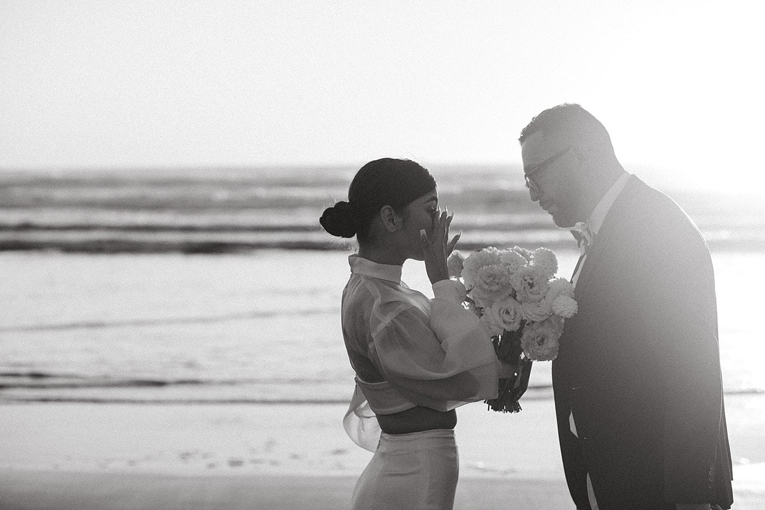 black and white portrait of emotional bride wiping away a tear during her vows at cannon beach elopement captured by marcela pulido portland oregon wedding photographer