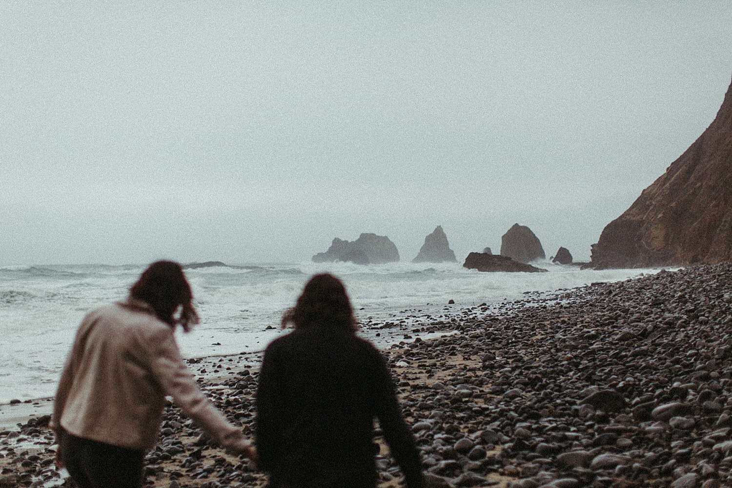 cinematic photo of a same sex lesbian couple walking away on the oregon coast by Marcela Pulido Portland Wedding Photographer