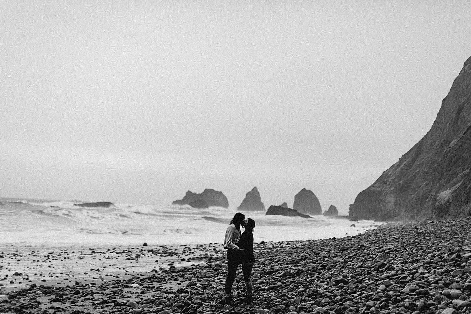 stunning and romantic black and white landscape photo of a same sex lesbian couple kissing on the oregon coast by Marcela Pulido Portland Wedding Photographer