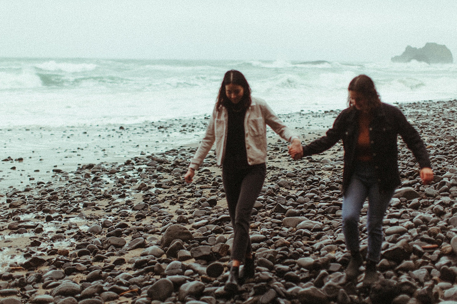 cinematic romantic shot of same sex lesbian couple walking on the coast holding hands in Oregon by Marcela Pulido Portland Wedding Photographer