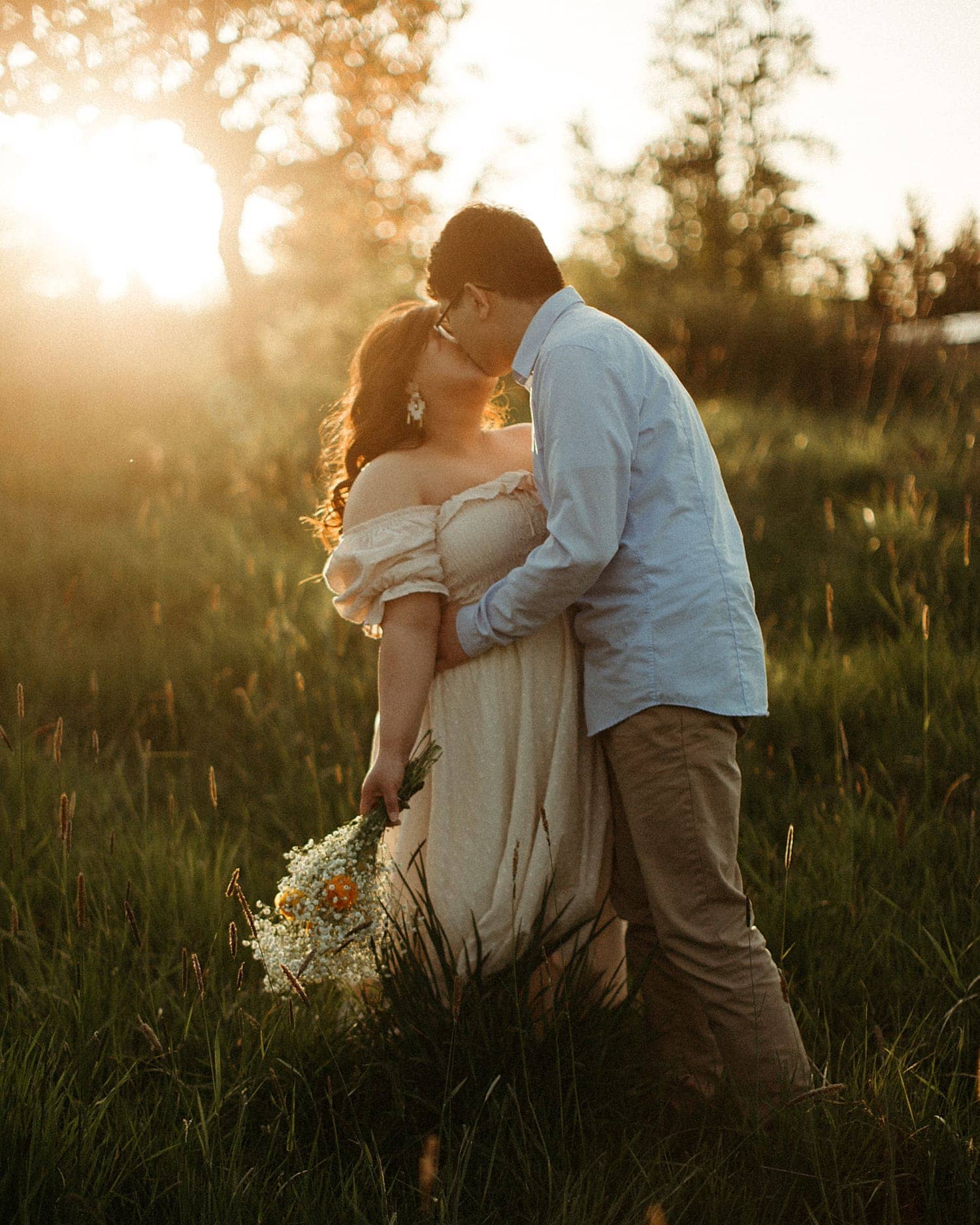 romantic and passionate kiss by adorable asian couple during golden hour light in a field cottagecore engagement session