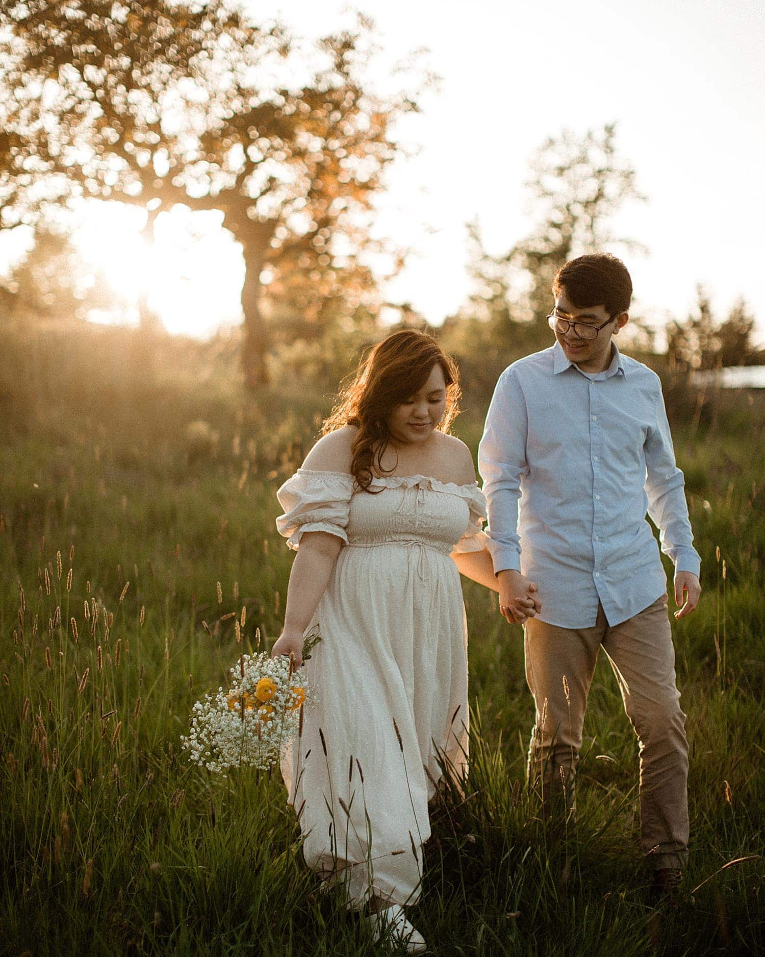 adorable asian couple walking in a field of grass at sunset cottagecore engagement session